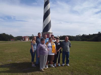 Residents and staff at an outdoor event near a lighthouse