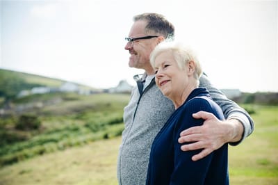 A man and woman standing together outdoors, smiling.