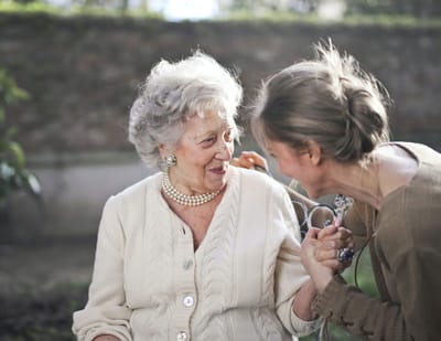 An elderly woman and a caregiver smiling and interacting