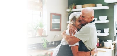 Two smiling seniors embracing in a bright kitchen