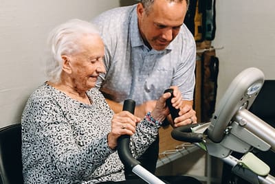 Staff assisting a resident with exercise equipment
