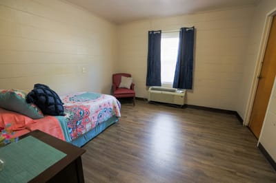 Private resident room with bed and armchair