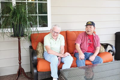 Two residents relaxing on a patio sofa
