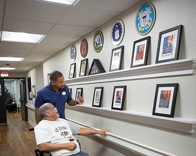 Resident engaging with staff in a hallway displaying photos