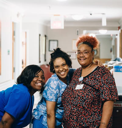 Three staff members smiling in a hallway