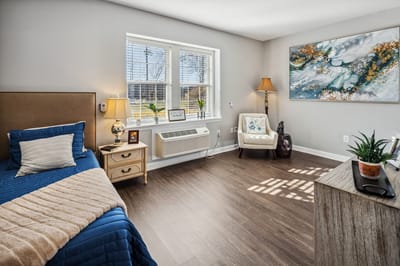 A cozy resident room with a bed and seating area