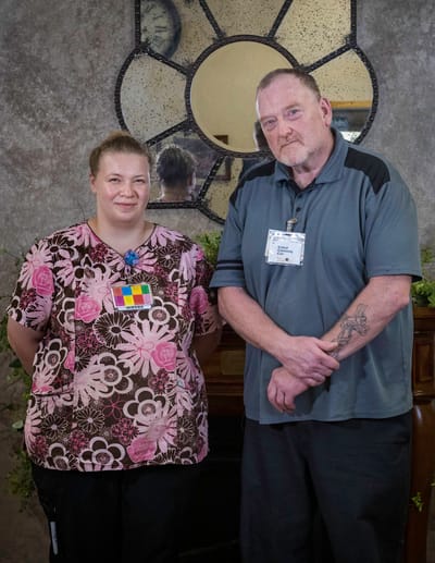 Two staff members posing in a facility lobby