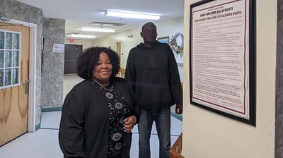 Residents smiling in a hallway with a rights poster