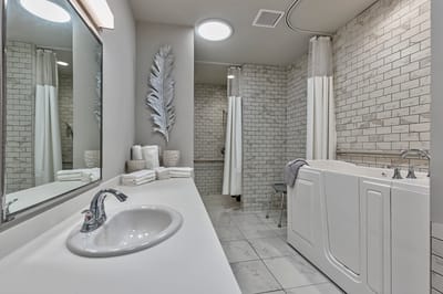 A modern bathroom with a walk-in tub and tiled walls