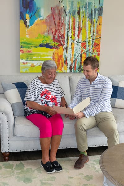 A resident and staff member reviewing a photo album in a cozy setting.