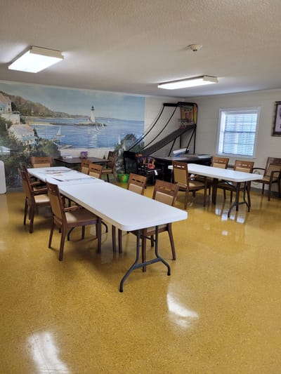 Bright activity room with tables and chairs arranged