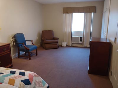 Private resident room with an armchair and air conditioning unit