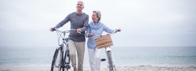 Older couple enjoying a walk on the beach with bikes
