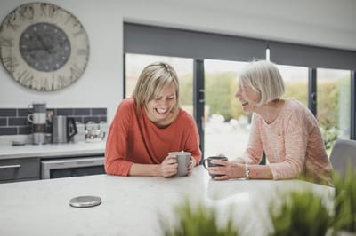 Two women enjoying coffee together in a facility kitchen