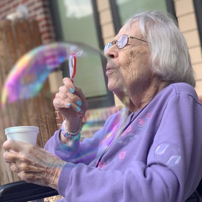 Elderly woman blowing bubbles outdoors