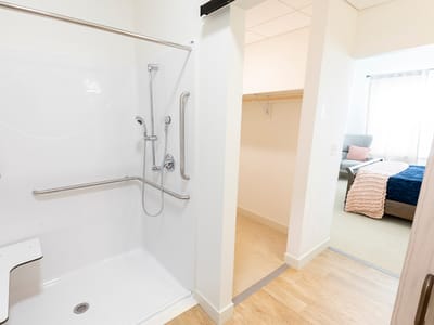 Private bathroom with grab bars and a bedroom visible