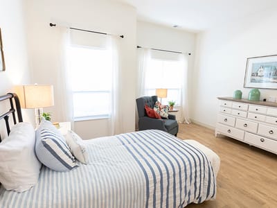 A well-furnished resident room with a bed and chair