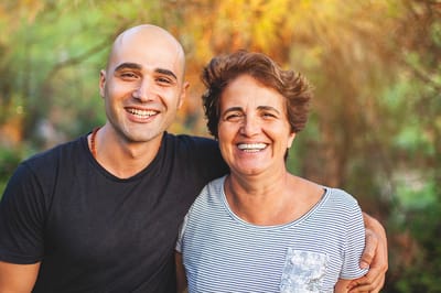 Two smiling individuals in a garden setting