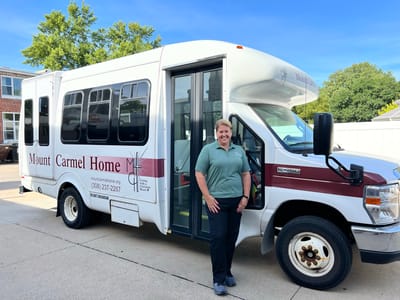 Staff member beside facility shuttle bus