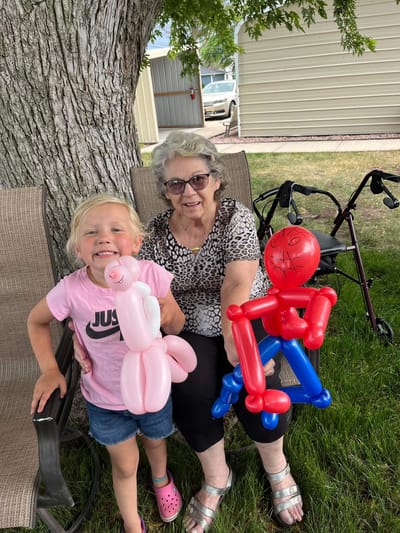 A resident and child with balloon animals in a garden