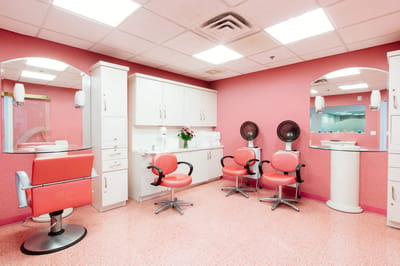 Bright hair salon area with red chairs and mirrors