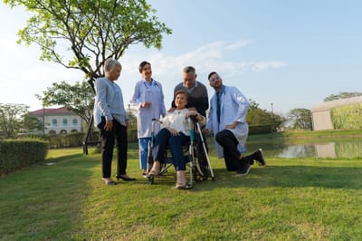 Healthcare staff assisting a resident outdoors.