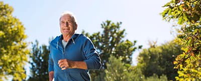 Senior man jogging in a sunny outdoor space