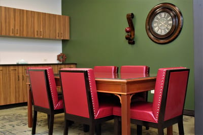 Cozy interior dining area with red chairs and wooden table.