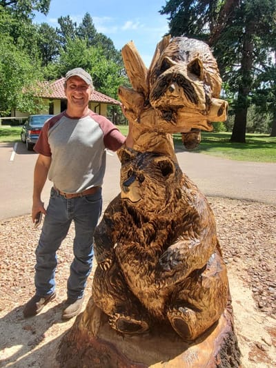 Man posing with a bear sculpture outdoors
