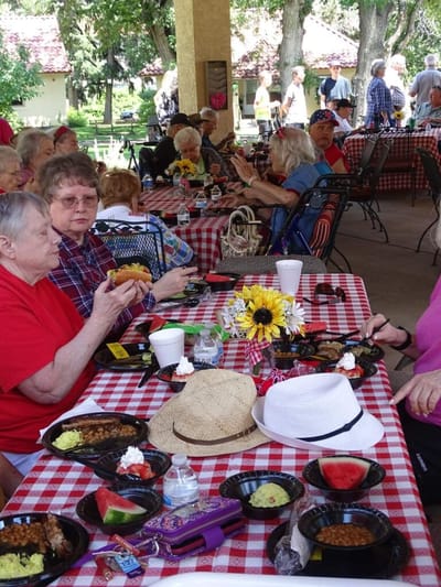 Residents enjoying a meal outdoors at tables.