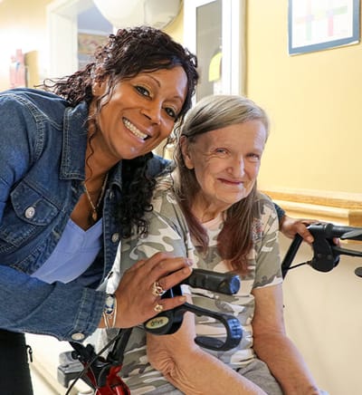 Staff smiling with a resident in a hallway