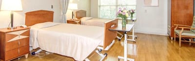 Well-furnished resident room with two beds and flowers.
