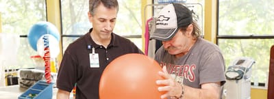 Therapist assisting a resident with a large ball
