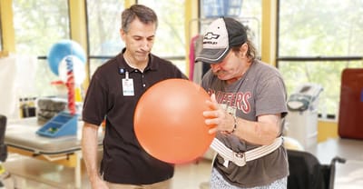 Staff assisting a resident with a therapy ball