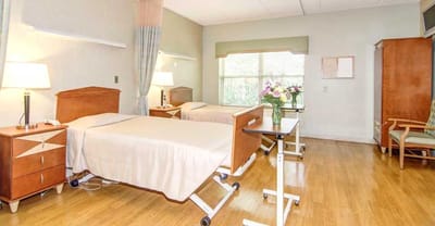 Private resident room with two beds and a floral arrangement.