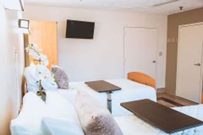 Clean, well-lit room with beds and tables.