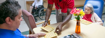 Residents participating in a bingo game with staff assistance.