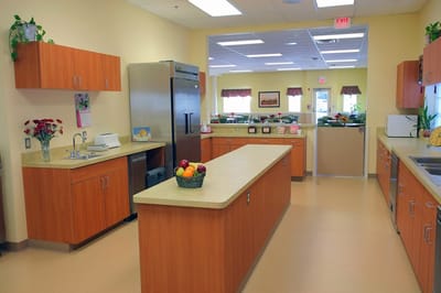 Bright kitchen area with cabinets and fruit basket.