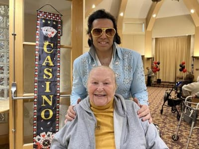 Resident smiling with a performer in a common area.