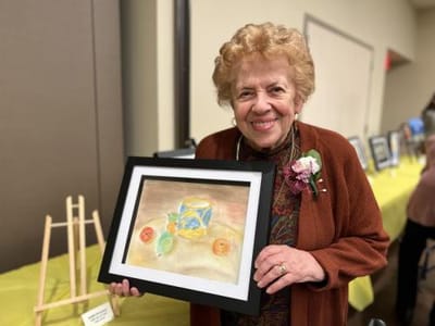 Senior woman proudly holding her artwork