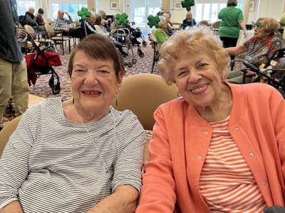 Two smiling elderly women in a common area
