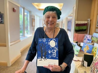 Resident showcasing a painting in a common area.