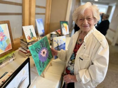 Resident displaying artwork at an activity event.