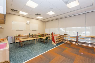 Bright indoor activity room with shelves and chairs.