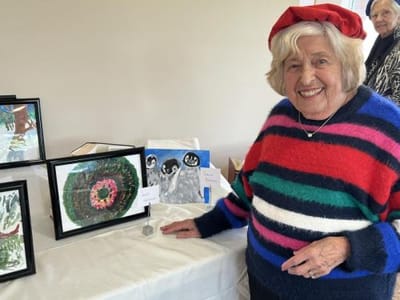 Resident showcasing artwork in communal area.