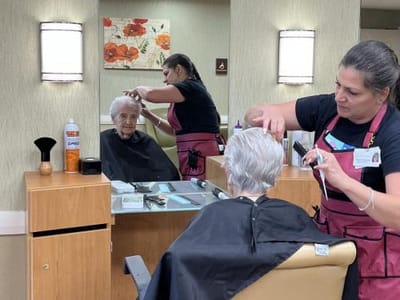 Resident receiving a haircut from staff member.