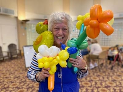 Senior resident joyfully holding balloon art.