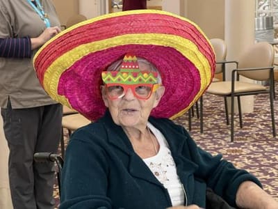 Elderly woman wearing colorful sombrero and glasses