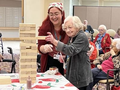 Resident and staff playing Jenga in a common area.