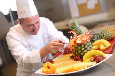 A chef artistically arranging a fruit display.